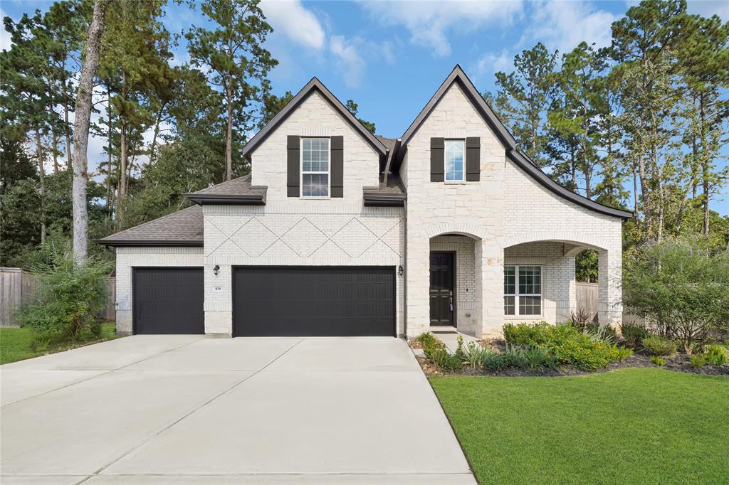 This is a two-story home featuring a stone and stucco facade, with a three-car garage and a landscaped front yard, nestled among tall trees in a serene neighborhood.