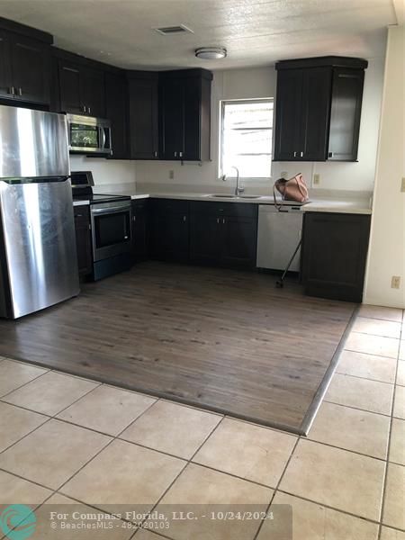 a kitchen with stainless steel appliances kitchen island granite countertop a sink and a refrigerator