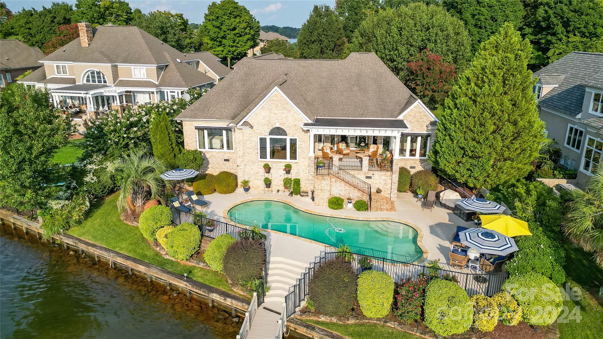 an aerial view of a house with swimming pool and large trees