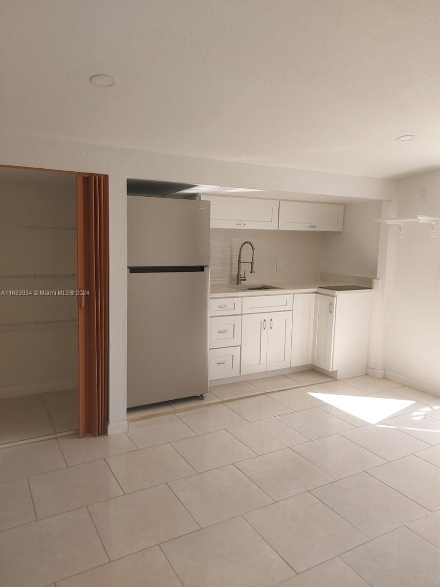 a view of kitchen with refrigerator cabinets and a refrigerator