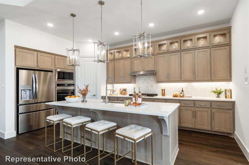 a kitchen with stainless steel appliances granite countertop a sink a stove a refrigerator cabinets and chairs