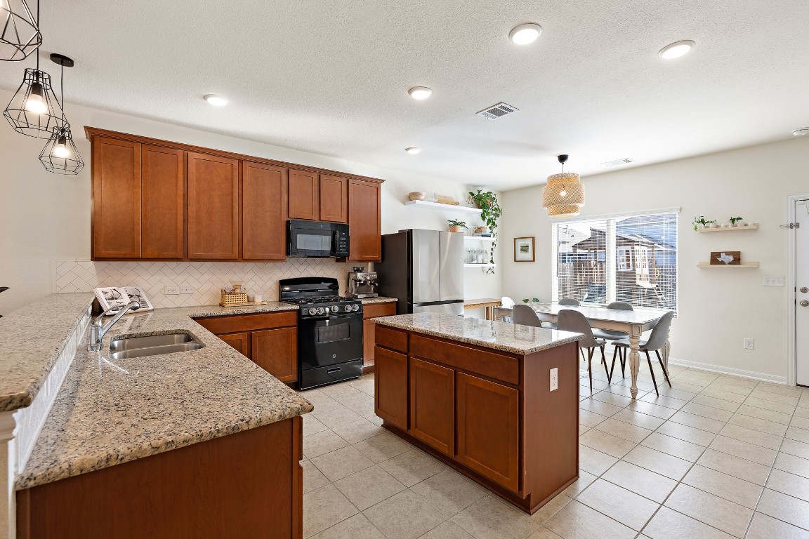 a kitchen with kitchen island granite countertop wooden cabinets and stainless steel appliances