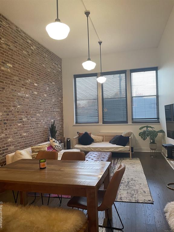 Dining area with dark hardwood / wood-style floors and brick wall