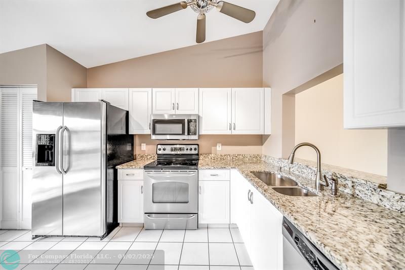 a kitchen with kitchen island granite countertop a stove a sink and a refrigerator