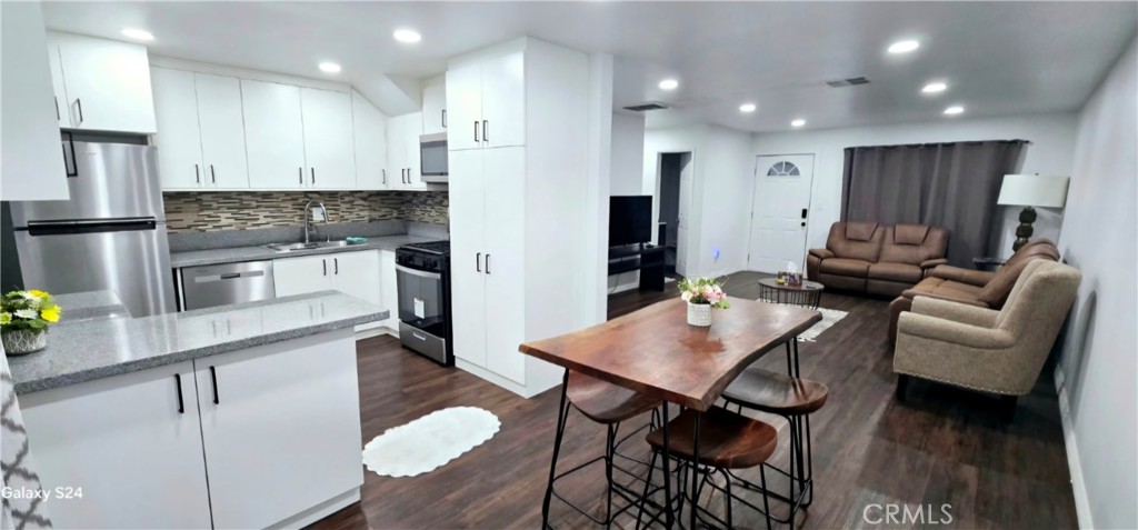 a kitchen with stainless steel appliances granite countertop a table chairs sink refrigerator and microwave