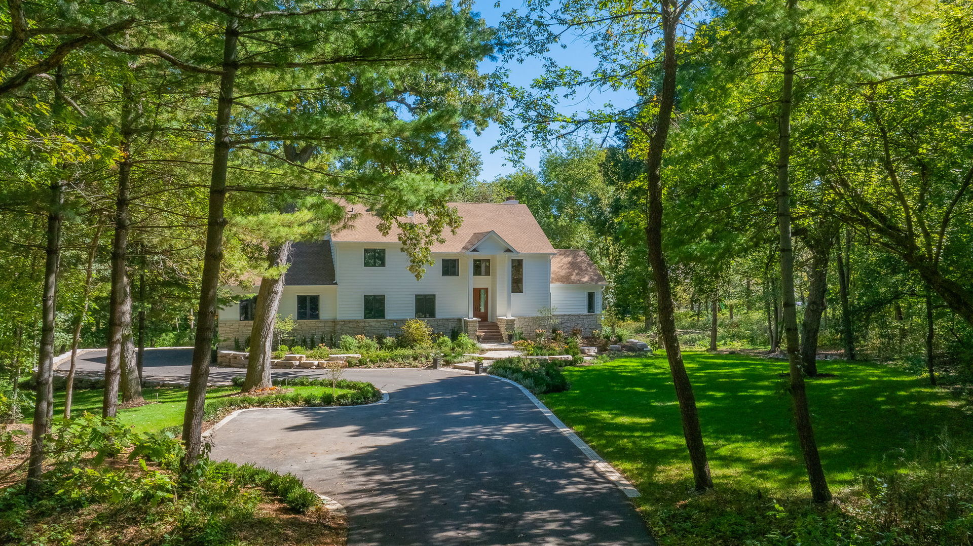 a front view of a house with a garden and trees