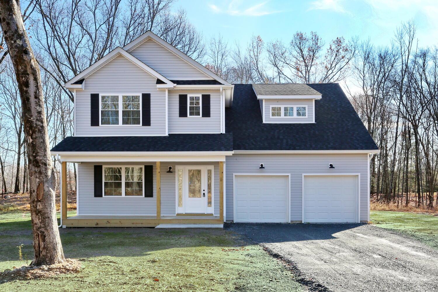 Front facade with covered porch, a front yard, and a garage