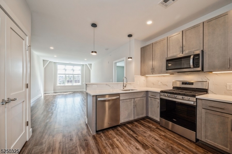 a kitchen with stainless steel appliances granite countertop hardwood floor sink stove and wooden cabinets