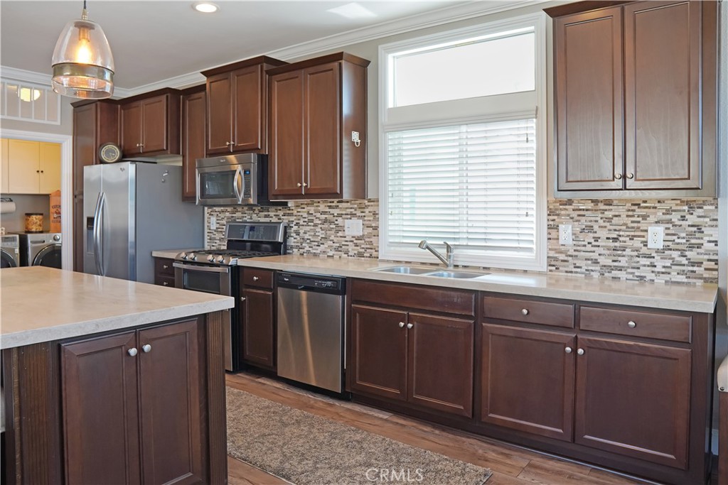 a kitchen with stainless steel appliances granite countertop wooden cabinets a sink and a window