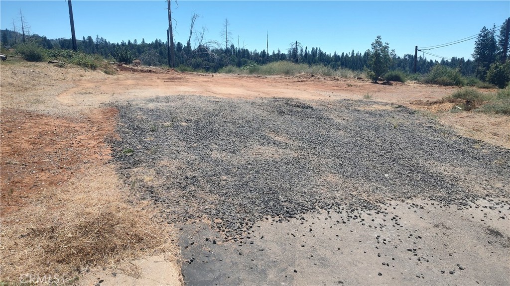 a view of dirt field with trees in the background