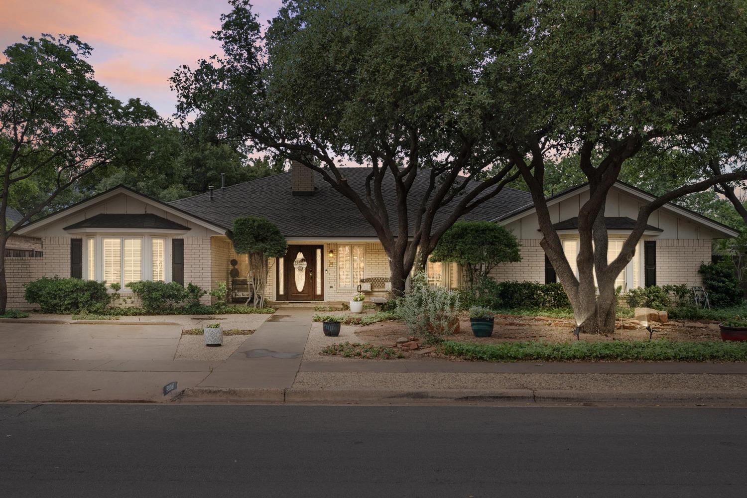 a front view of a house with yard and trees