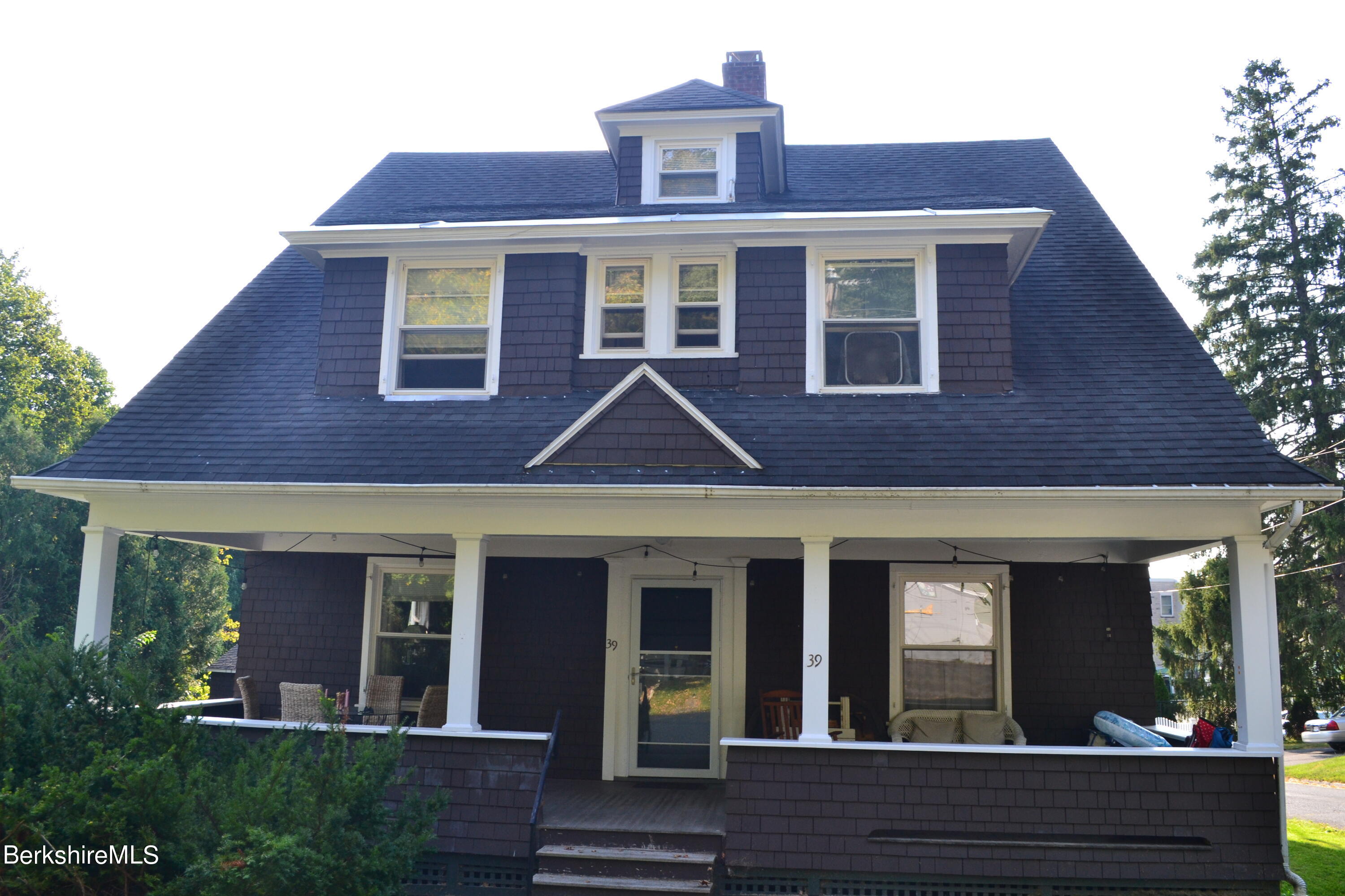 a view of a brick house with large windows and a small yard