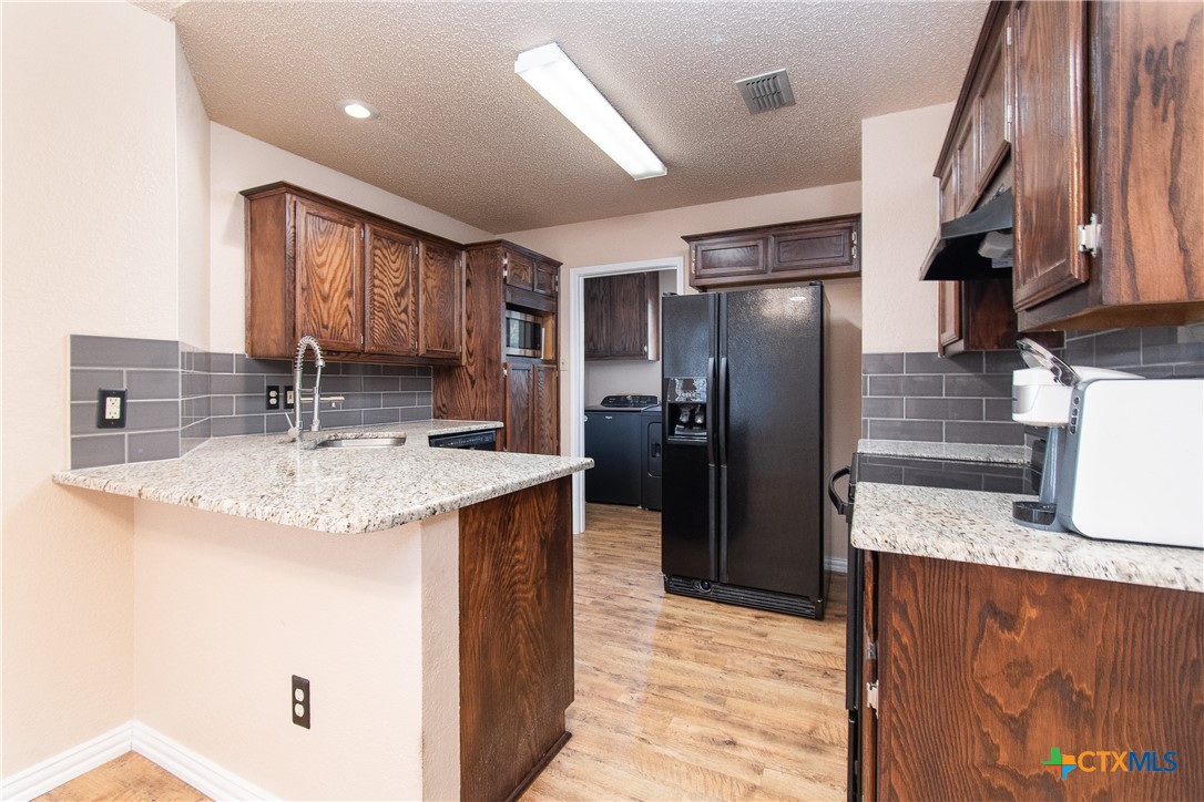 a kitchen with stainless steel appliances granite countertop a sink refrigerator and cabinets