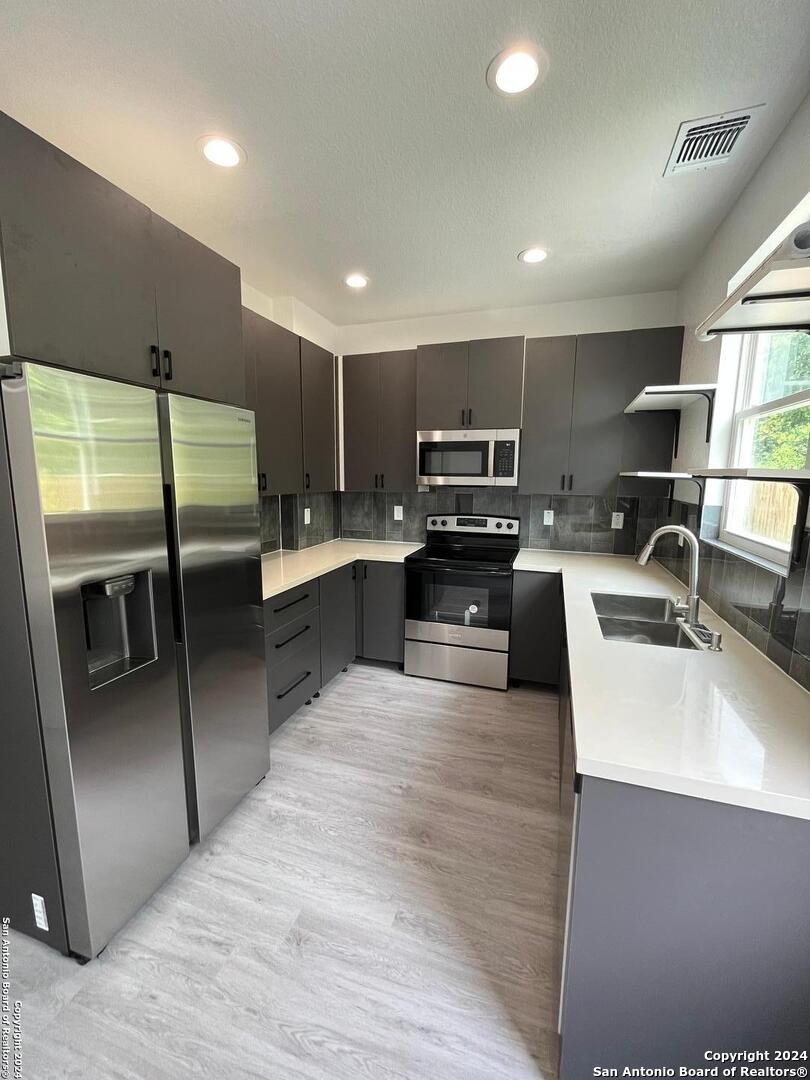 a large kitchen with a large window and stainless steel appliances