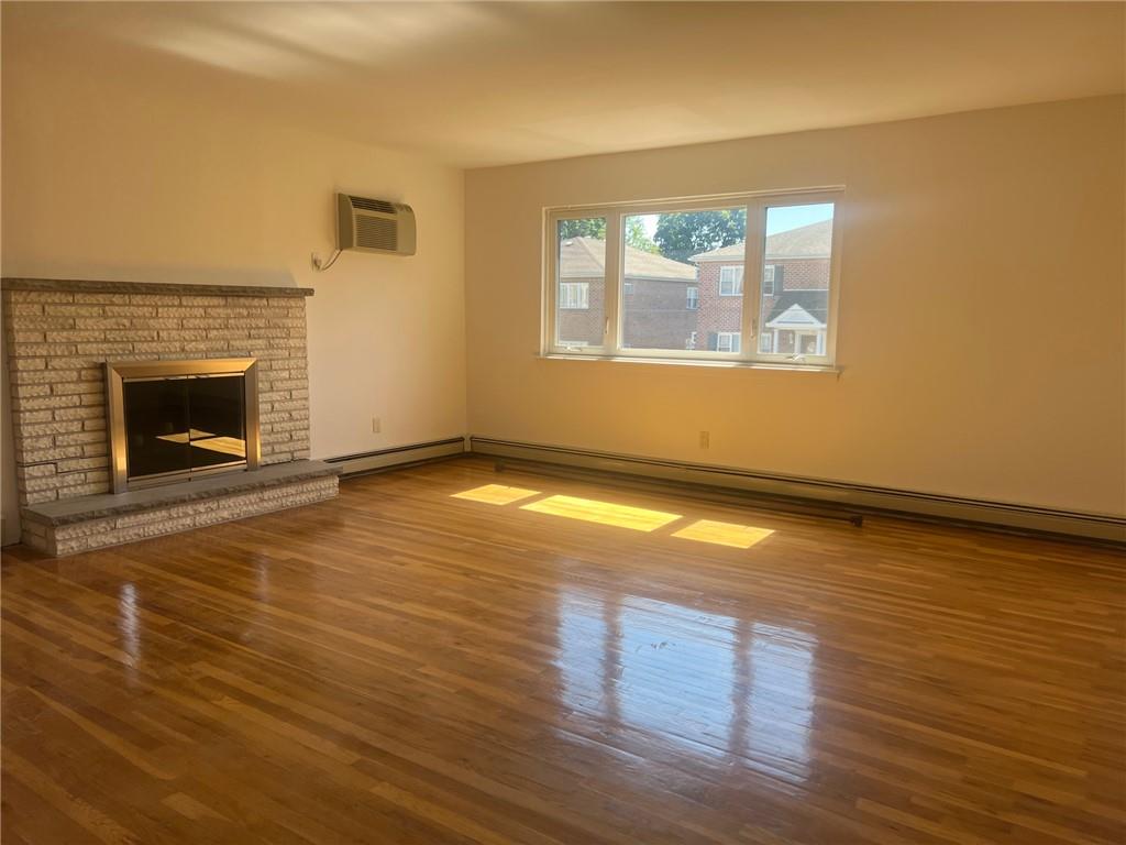 an empty room with wooden floor fireplace and windows