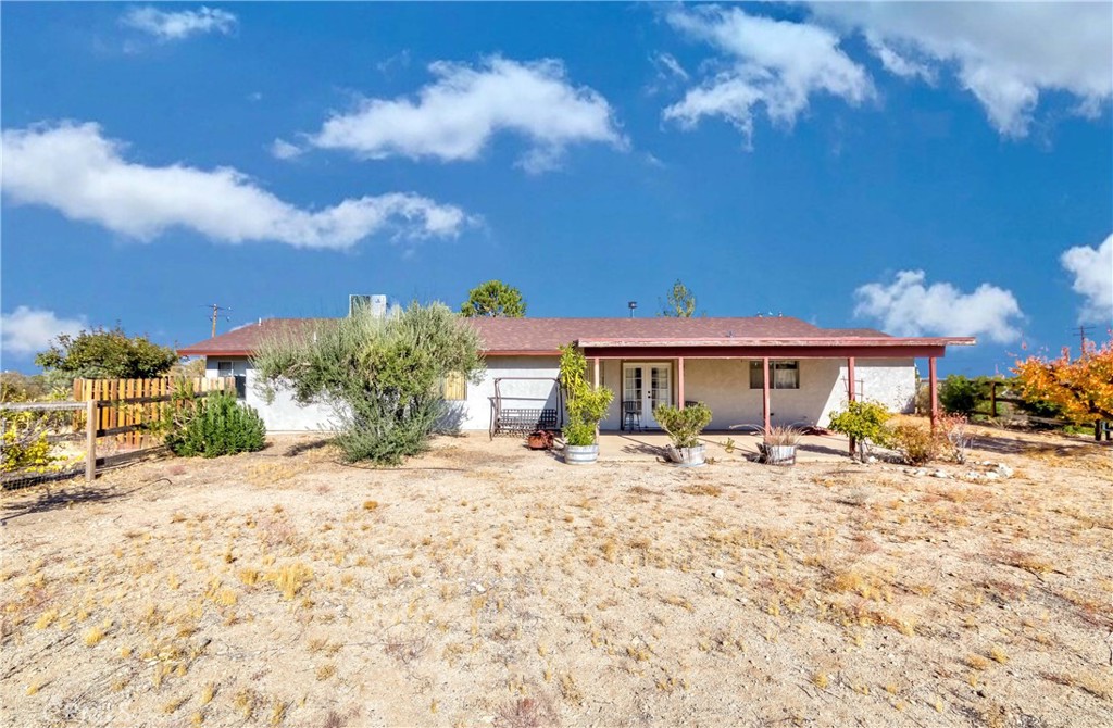 a front view of a house with a dirt yard and a large tree