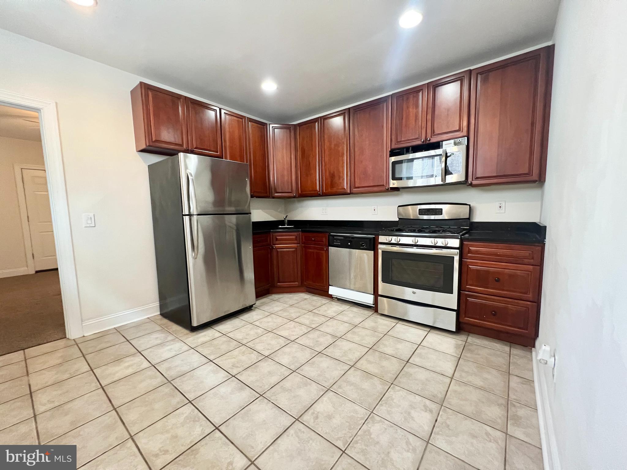 a kitchen with stainless steel appliances granite countertop a refrigerator stove top oven a sink and dishwasher