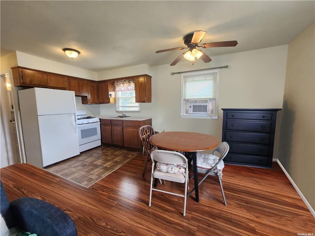 Kitchen with dark wood-type flooring, cooling unit, sink, white appliances, and ceiling fan