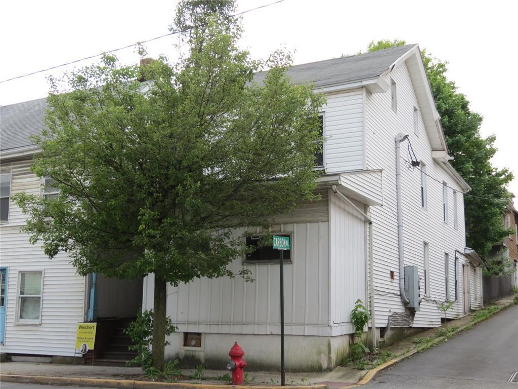 a view of a white house with a small yard and large tree