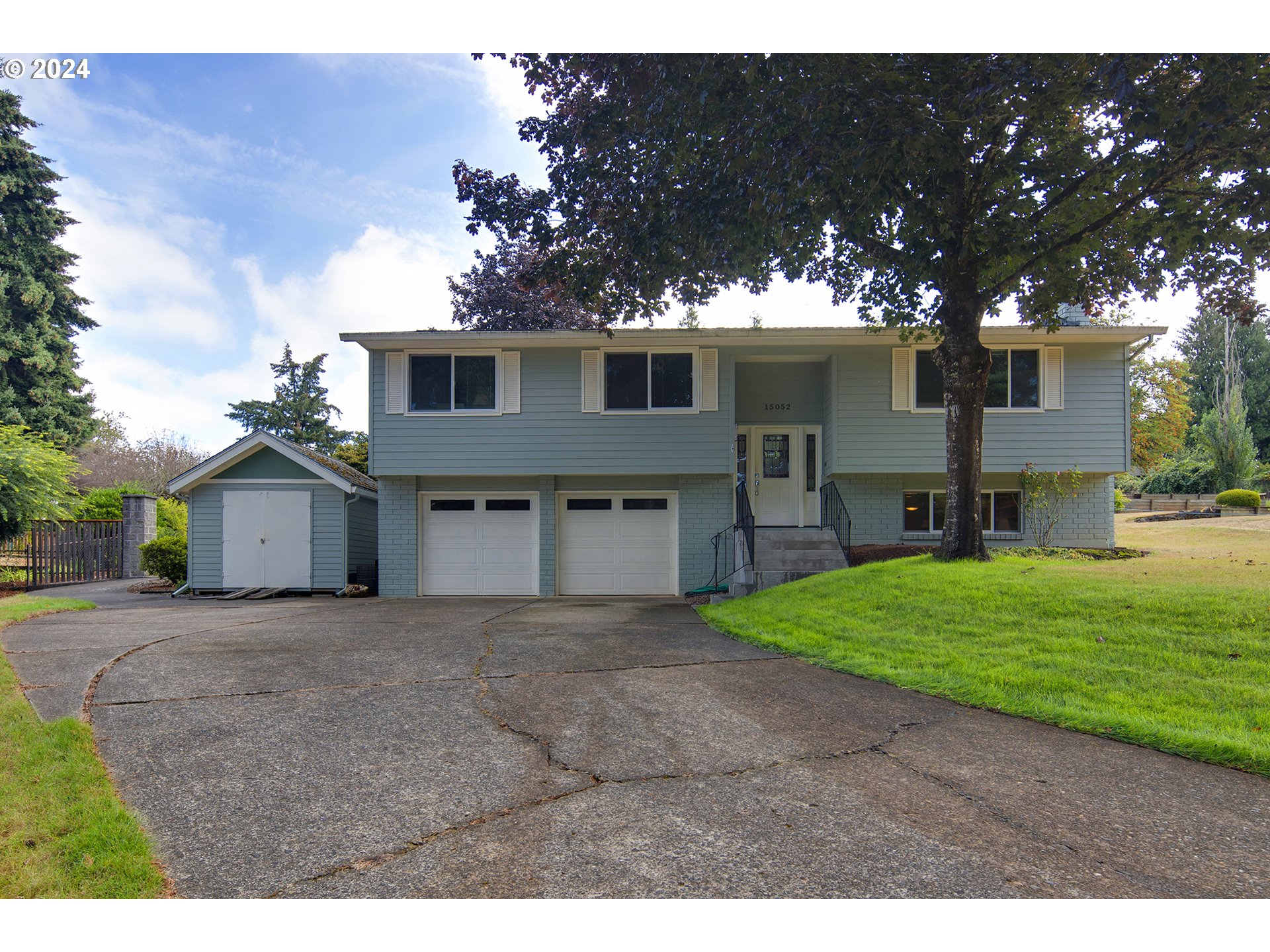 a view of a house with a yard and large tree