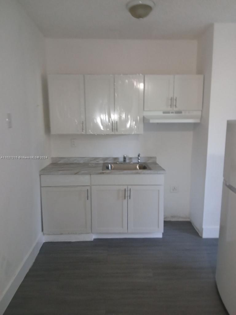 a kitchen with granite countertop white cabinets and a sink