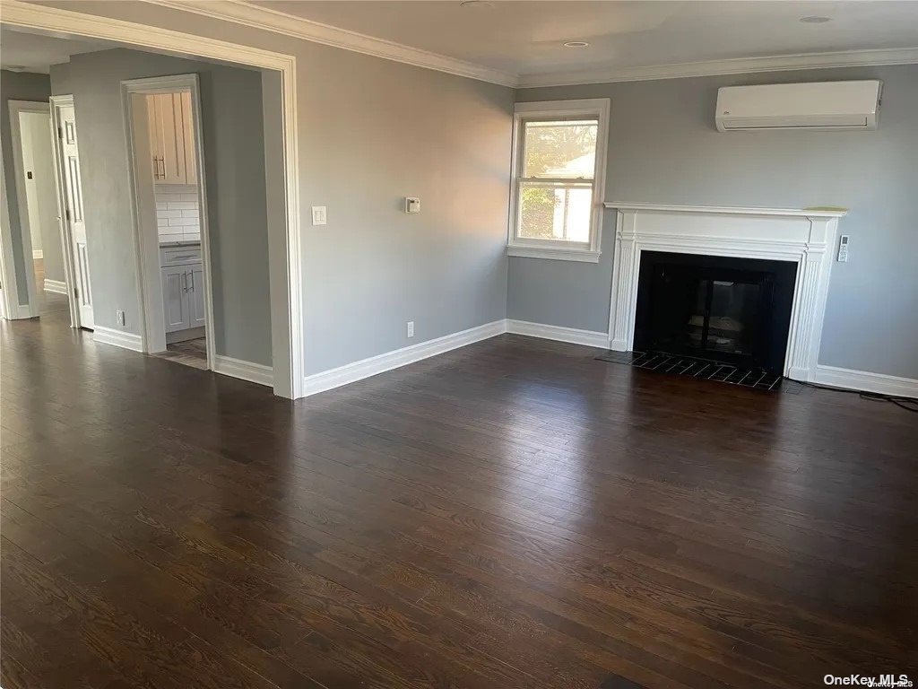 an empty room with wooden floor fireplace and windows