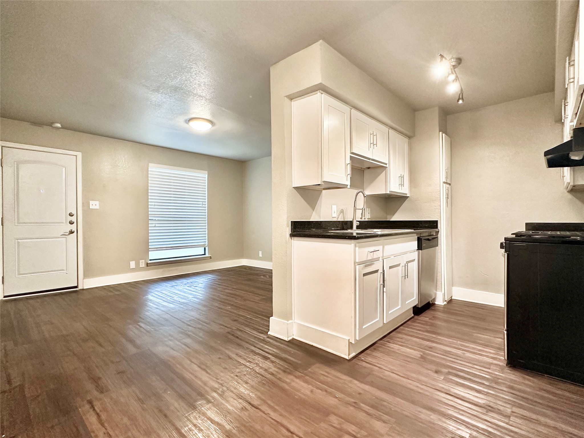 a kitchen with white cabinets and a wooden floor