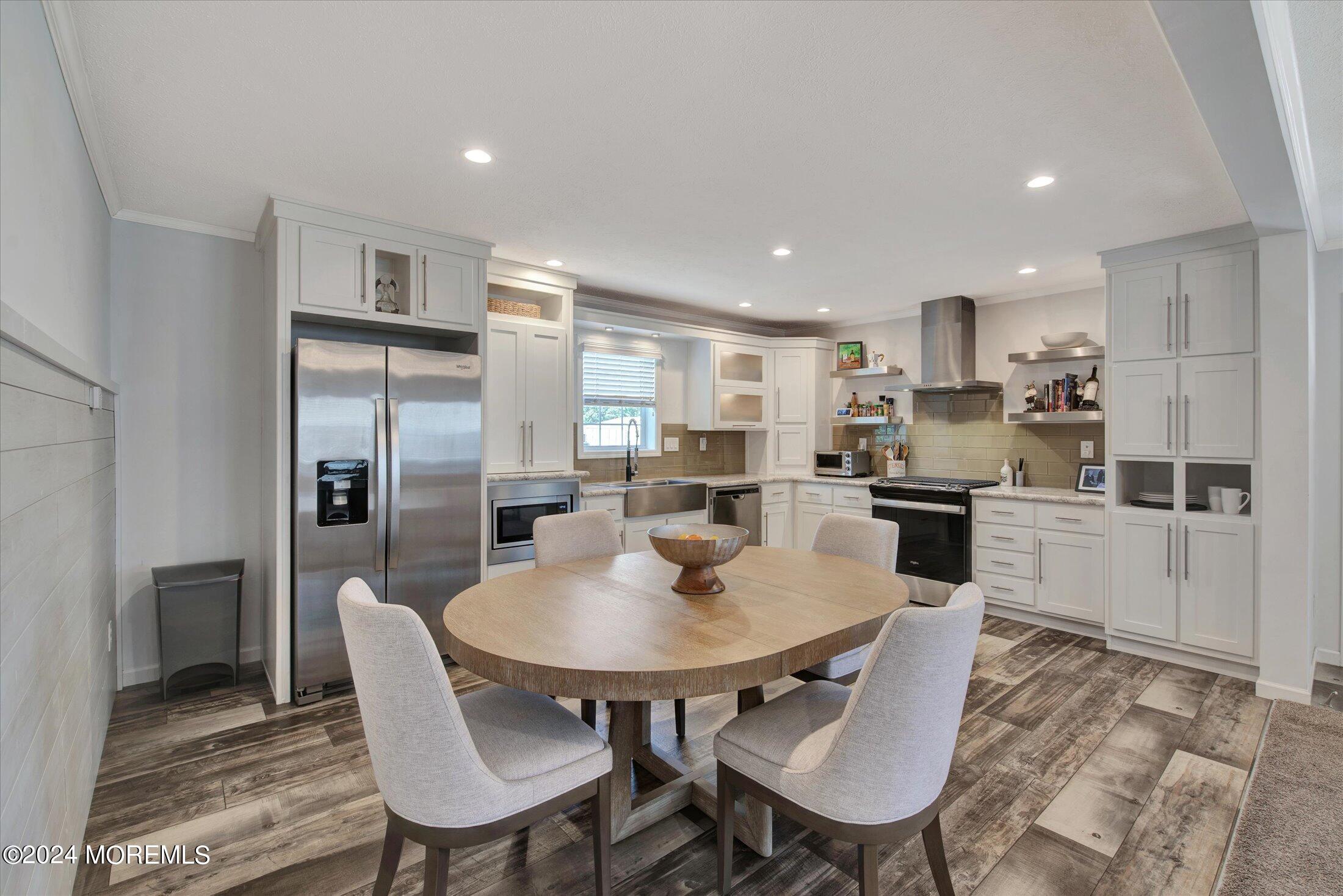 a kitchen with stainless steel appliances granite countertop a dining table chairs refrigerator and cabinets