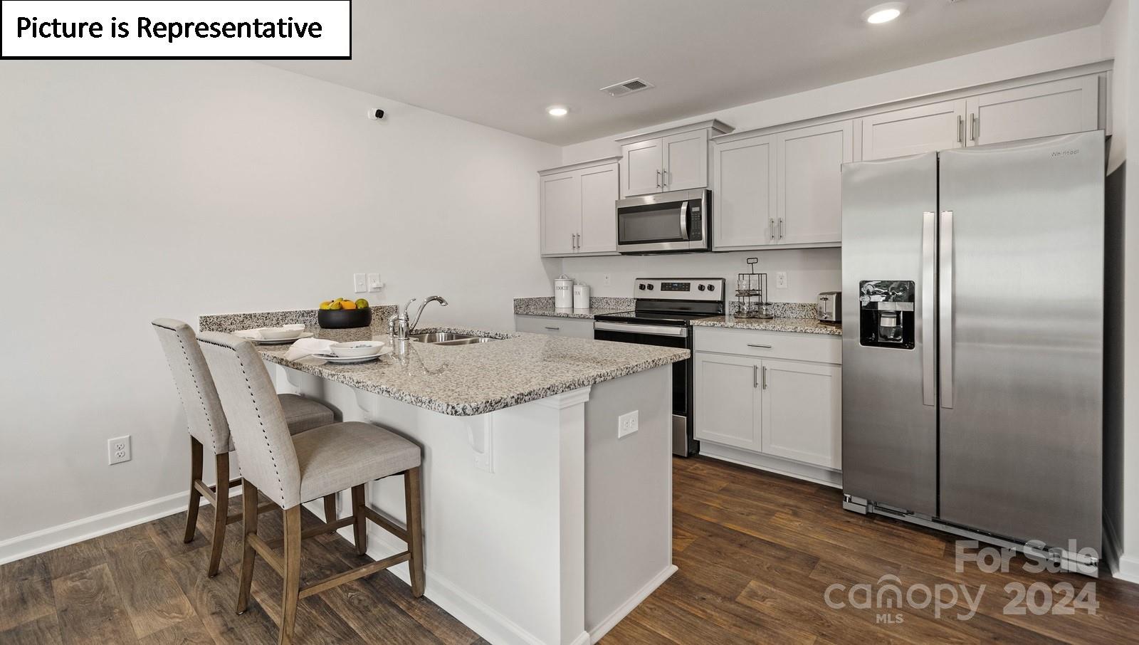 a kitchen with stainless steel appliances a white table chairs and a refrigerator