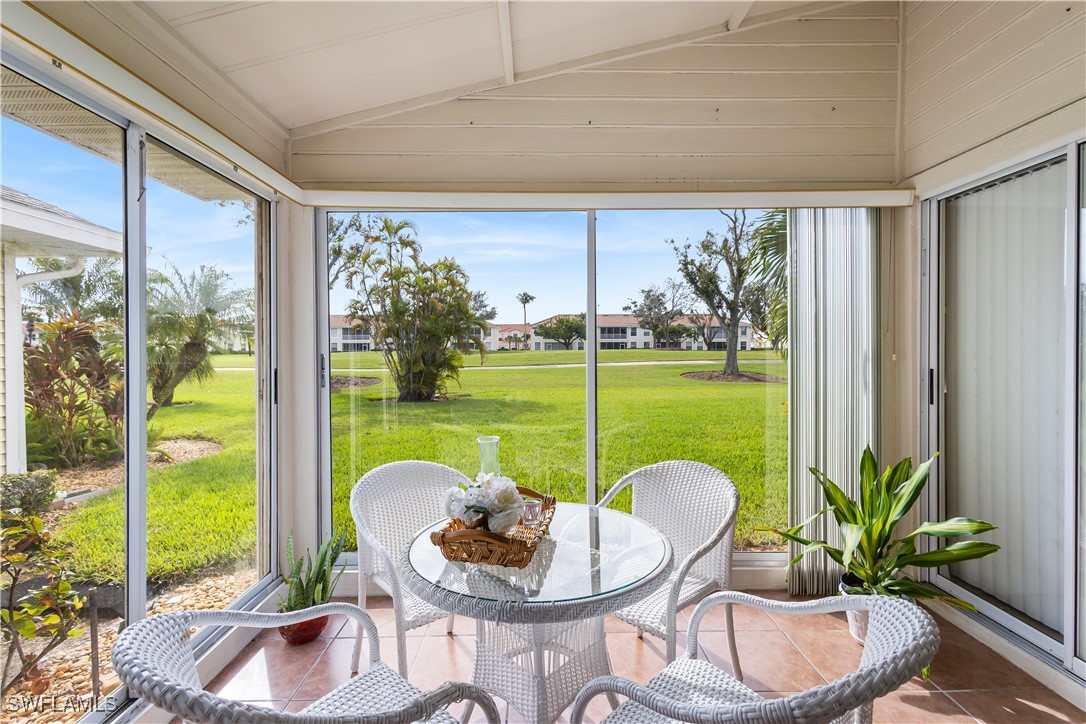 a patio with table and chairs potted plants and a floor to ceiling window