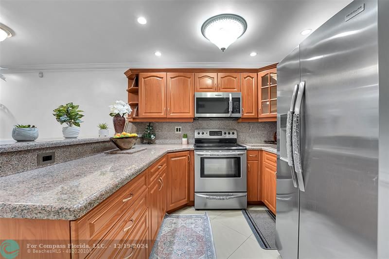 a kitchen with stainless steel appliances granite countertop a sink stove and refrigerator