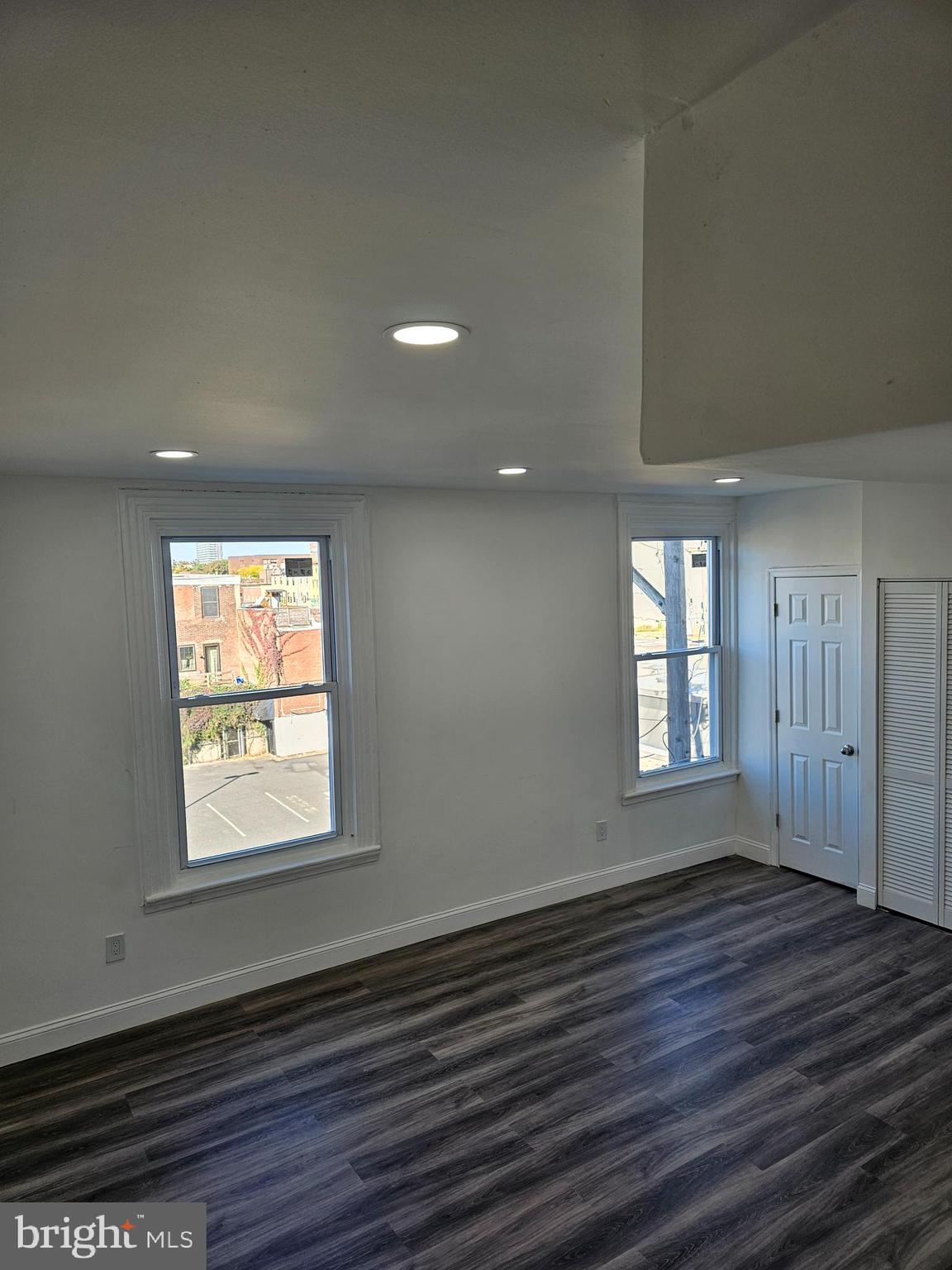 an empty room with wooden floor and windows