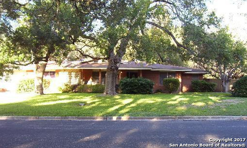 a view of a house with a yard and large trees