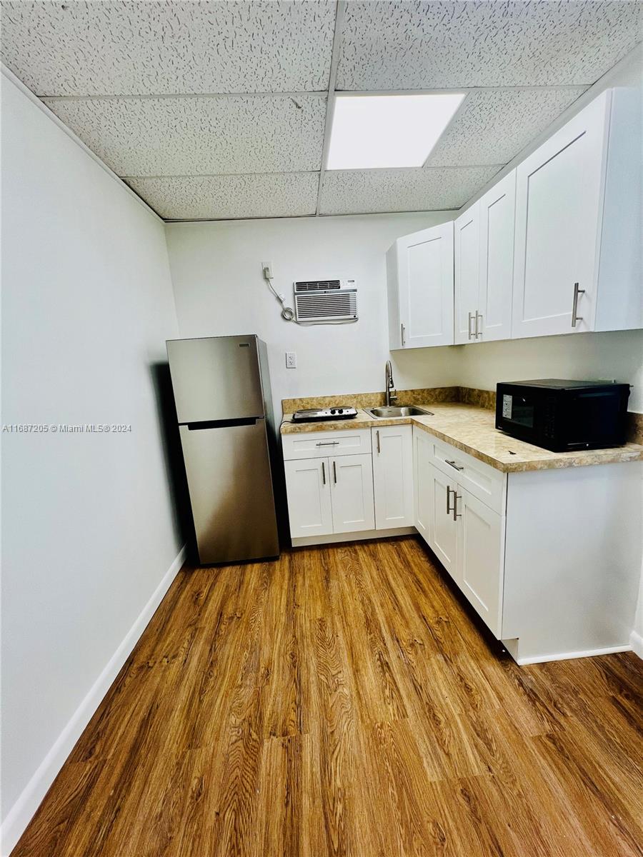 a kitchen with a sink a stove top oven and white cabinets