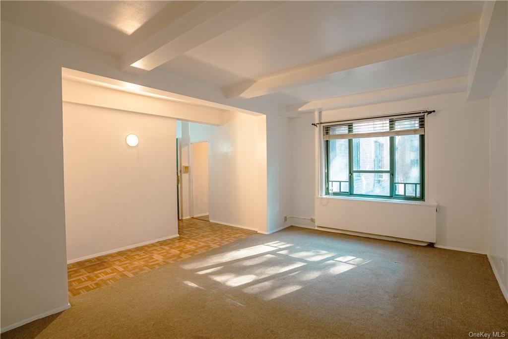 Spare room featuring beam ceiling and light parquet floors