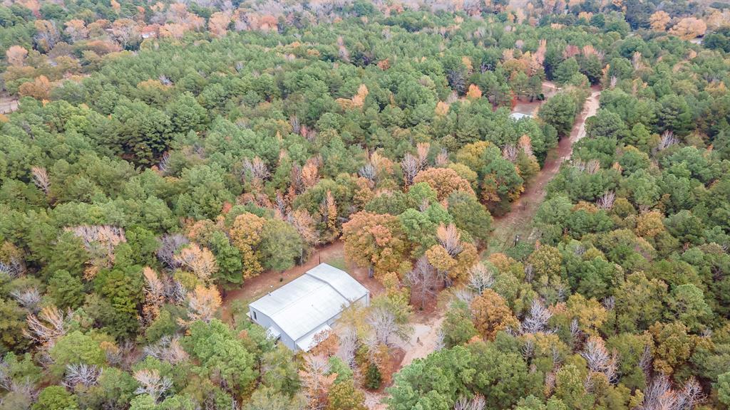 an aerial view of residential house with outdoor space and trees all around