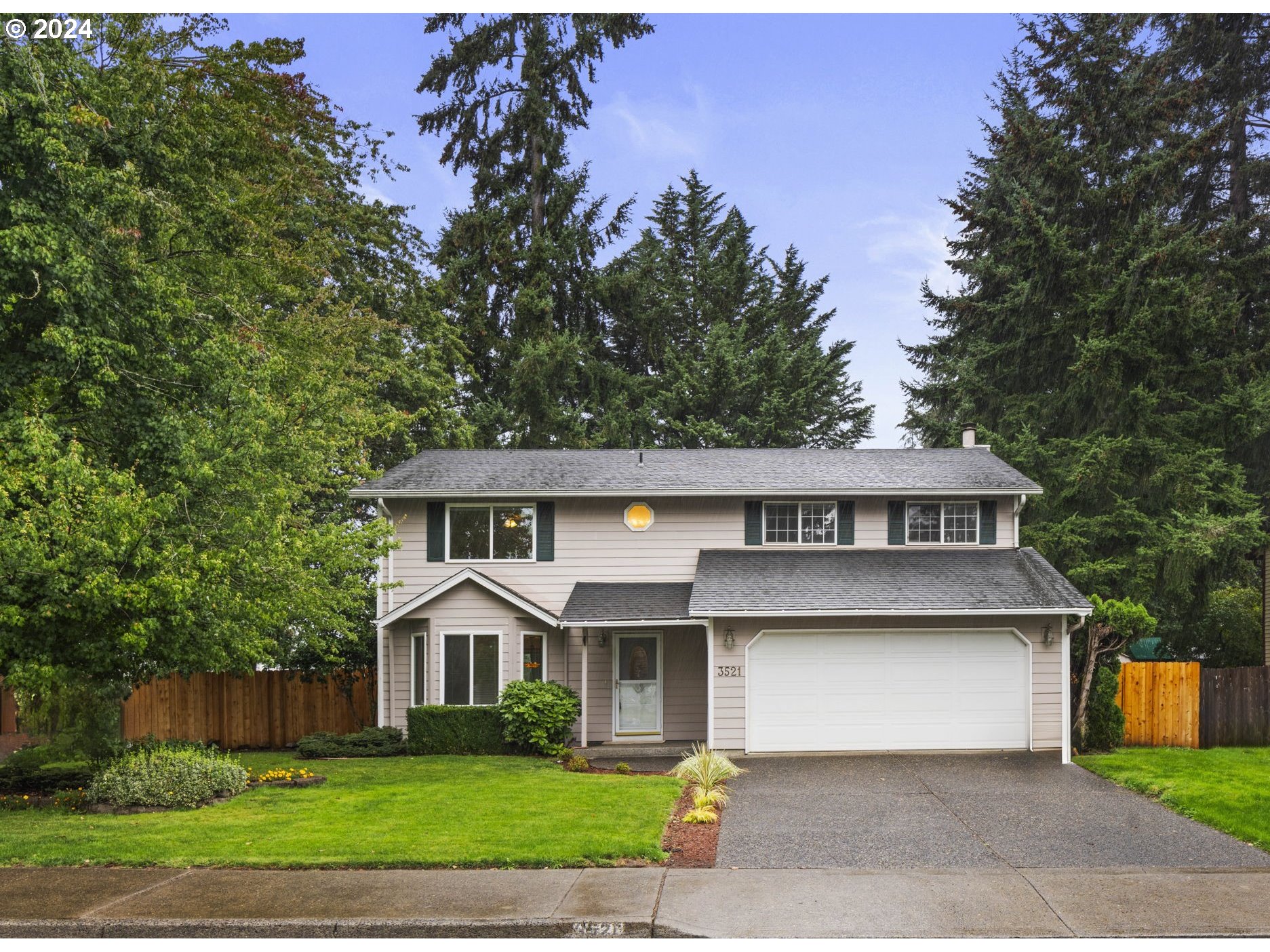 a front view of a house with a garden and trees