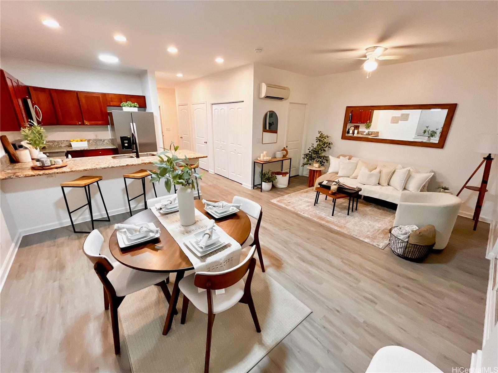 a living room with furniture kitchen view and a wooden floor