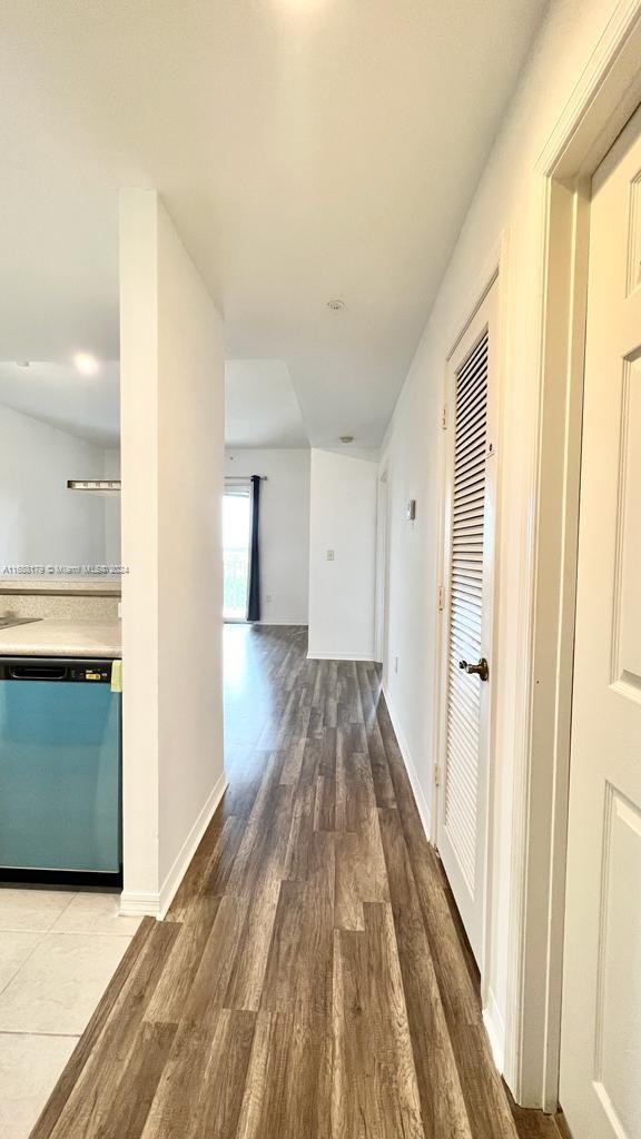 a view of a hallway with wooden floor and a kitchen