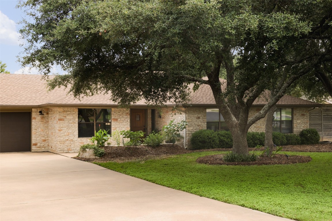 a front view of a house with a garden and trees