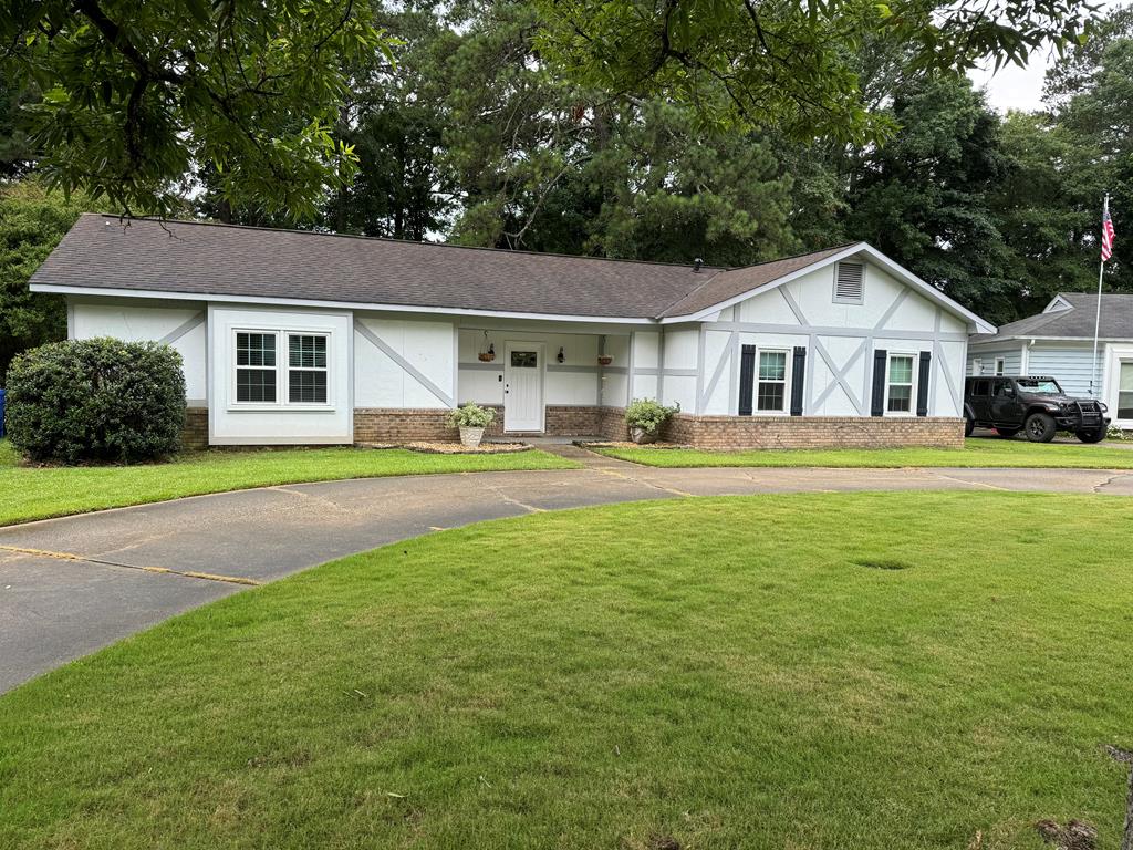 a front view of a house with a garden and trees