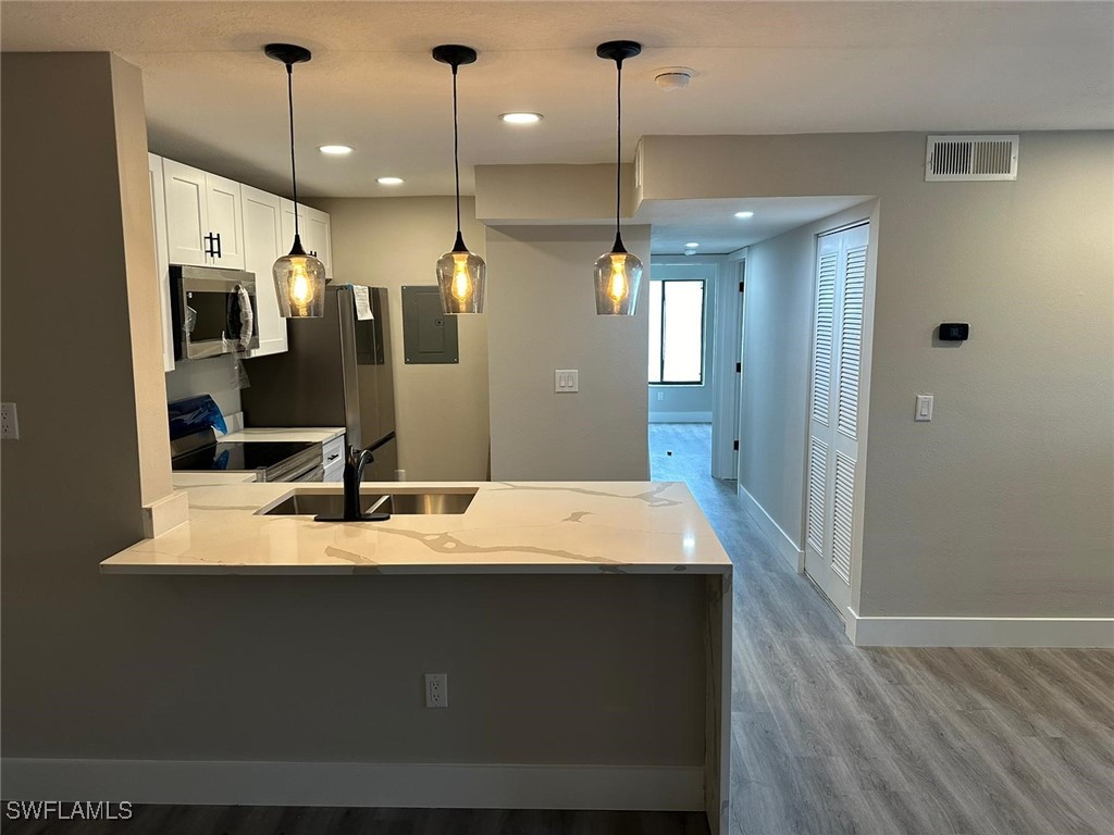 a large kitchen with a refrigerator a sink and wooden floor