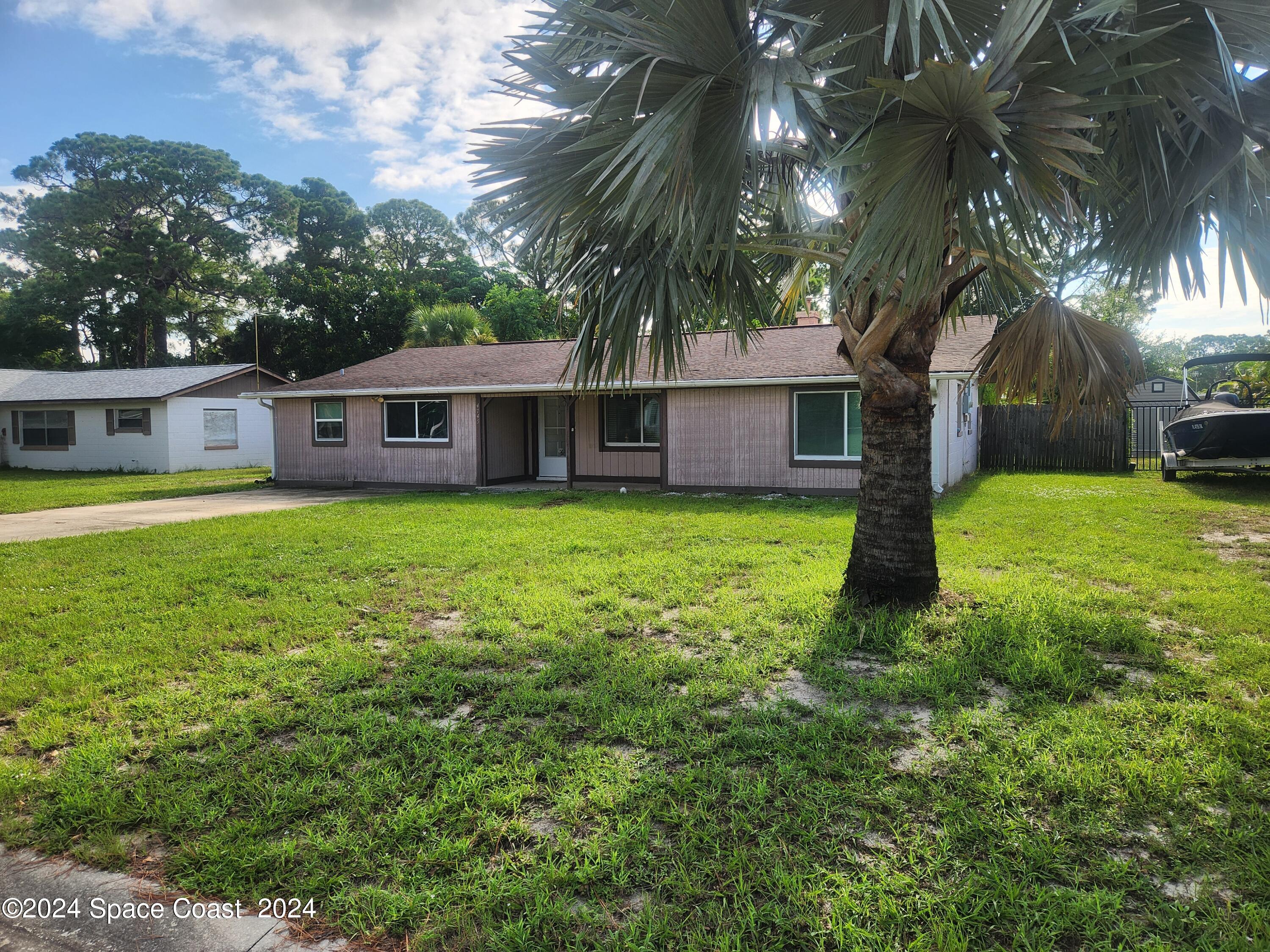 a view of a house with a big yard and palm trees