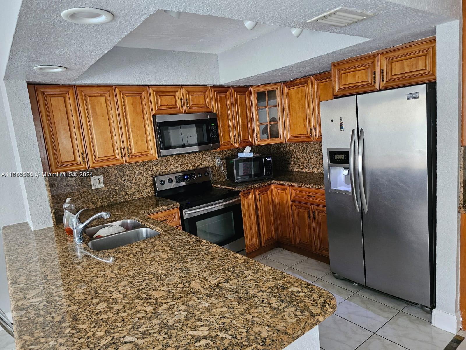 a kitchen with stainless steel appliances granite countertop a refrigerator and a sink