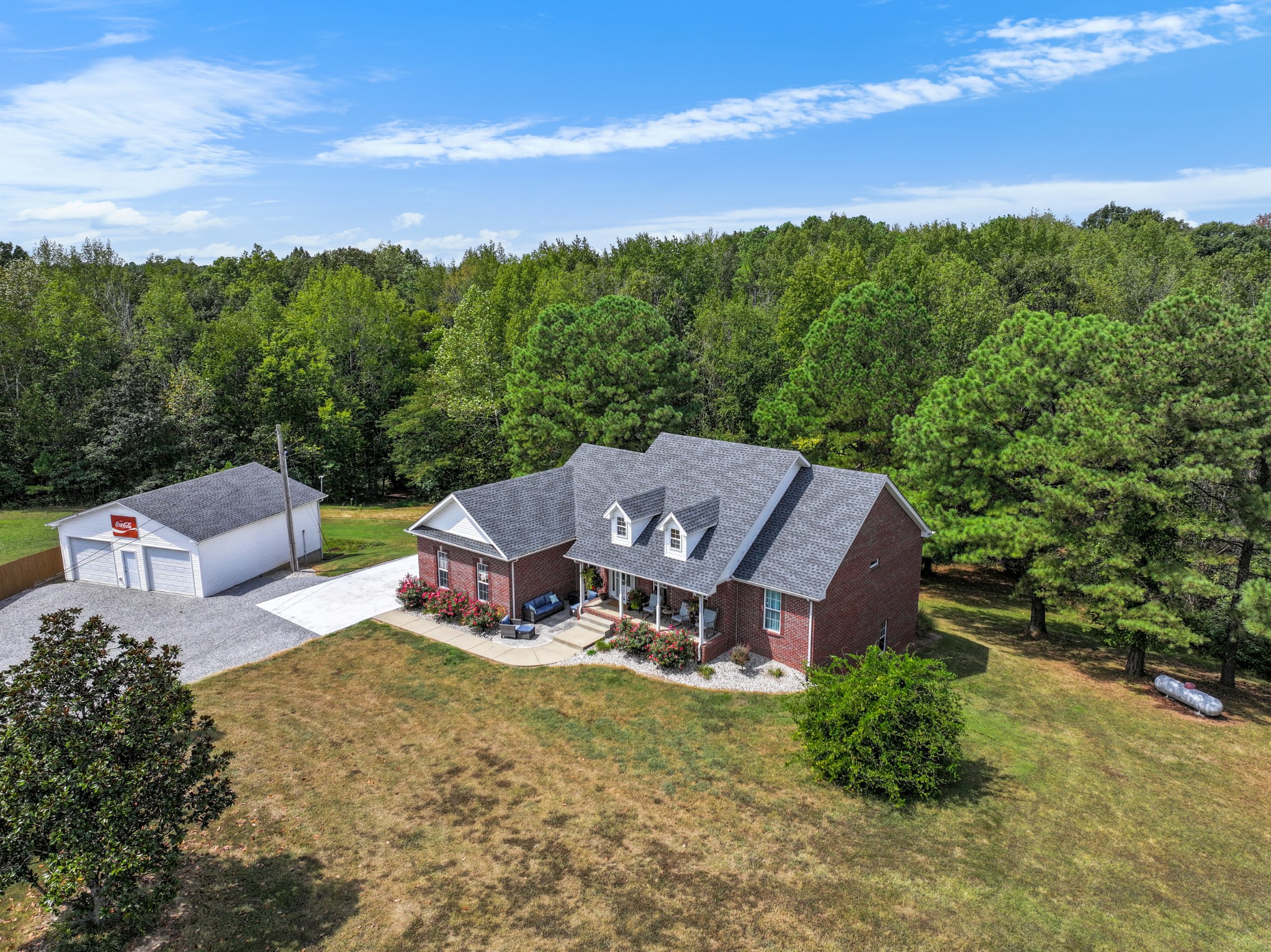 an aerial view of a house with garden space and trees in the background