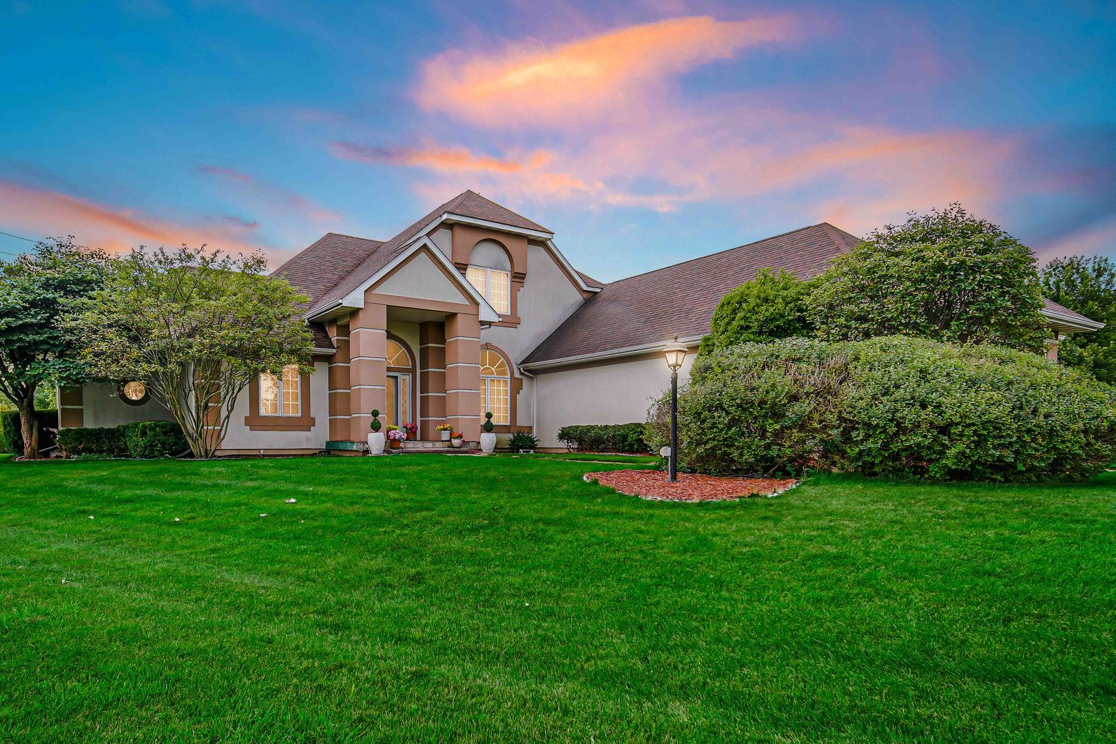 a front view of a house with a yard and green space