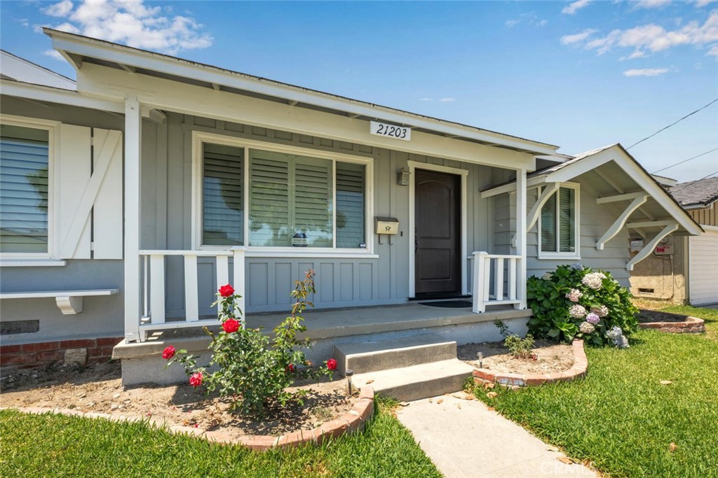 a front view of house and yard with beautiful flowers and seating