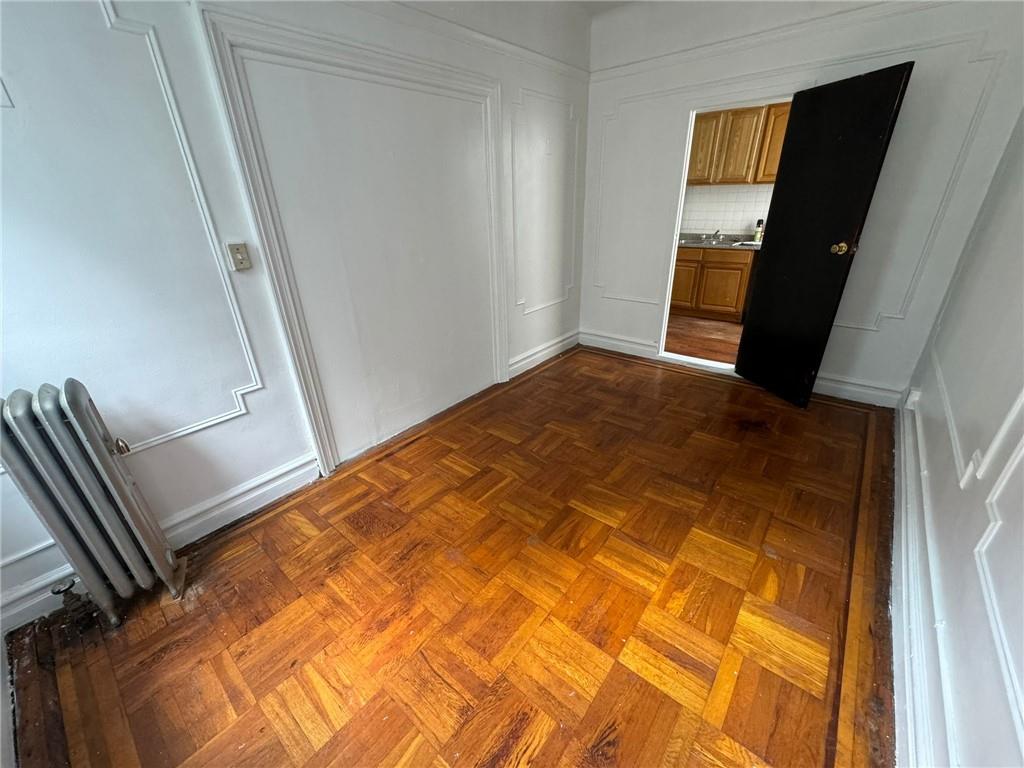 Empty room featuring dark parquet flooring and radiator