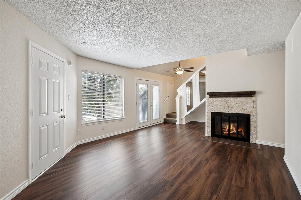 a view of an empty room with wooden floor fireplace and a window