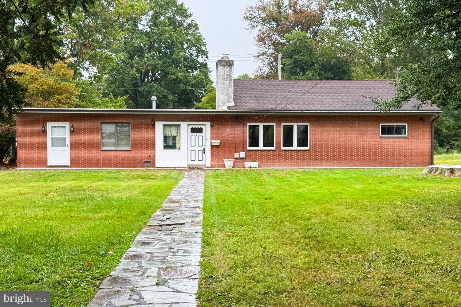 a front view of a house with a yard and trees